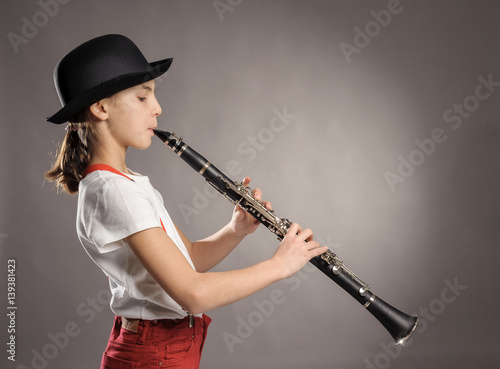 little girl playing clarinet on a gray background