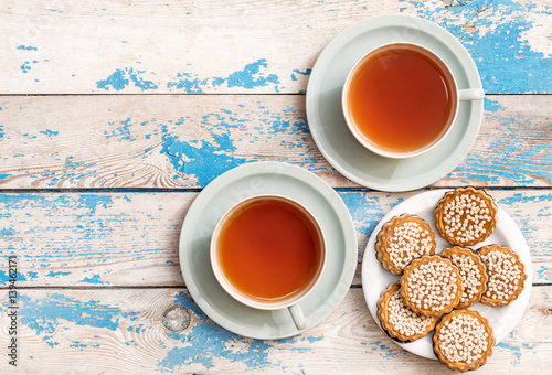 Two cup of tea and saucer with cookies on the table. Top view.