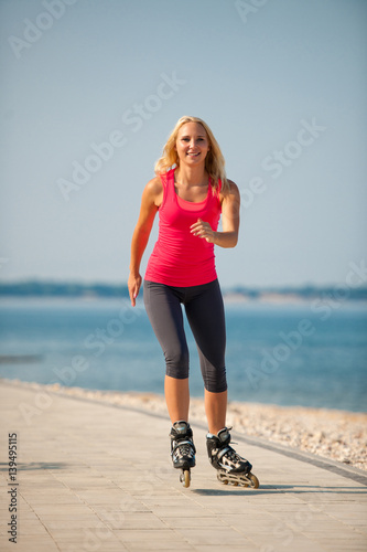 Two women exercise on beach running and rollerblade skating near sea