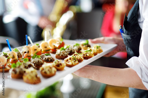 Waiter carrying plates with meat dish on festive event, party or wedding reception