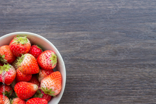 Fresh strawberry in cup on wooden background.