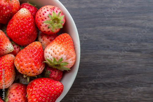 Fresh strawberry in cup on wooden background.