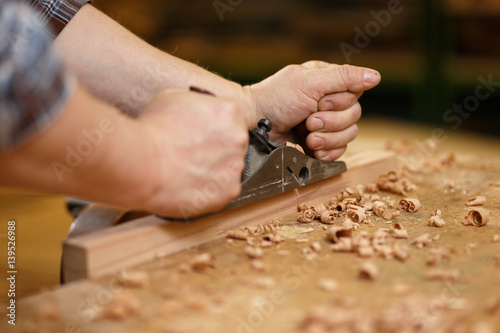 Carpenter working with planer on the workbench 