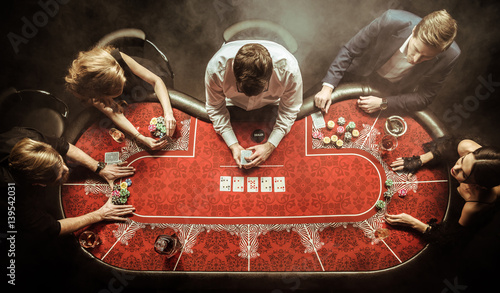 top view of men and women playing poker in casino