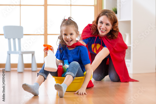 Preschooler kid girl and her mother playing while doing cleanup at home