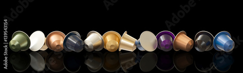 Different color coffee capsules in black bottom row. aroma, taste, choice