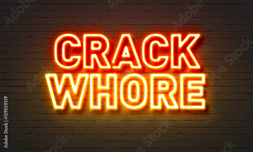 Crack whore neon sign on brick wall background.