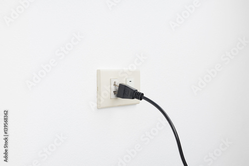 Loose plug and falling from outlet electric shock on white wall background, check and safety electricity household concept