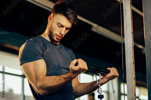 Handsome man doing heavy weight exercise for biceps in the gym