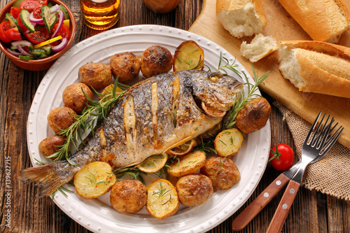 Grilled fish with baguette and vegetables on the plate
