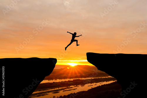 Courage man jumping over cliff on sunset background,Business concept idea