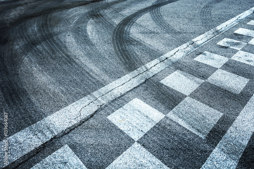 Zakończ i rozpocznij wyścigi linii wzorcowych na tle drogi asfaltowej ze skrzyżowaniem śladów opon.