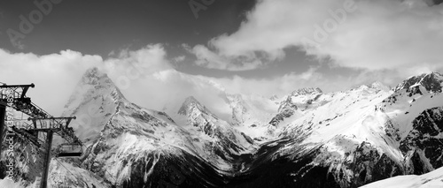 Black and white panoramic view on snow mountains in clouds