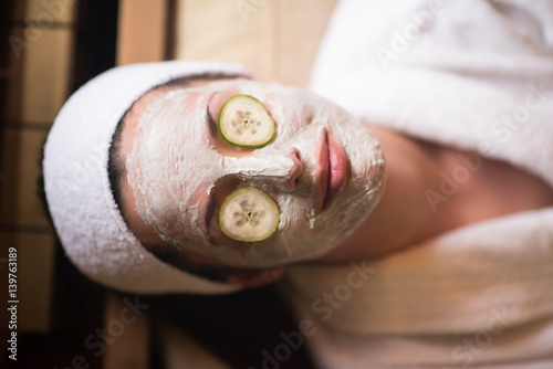 woman is getting facial clay mask at spa