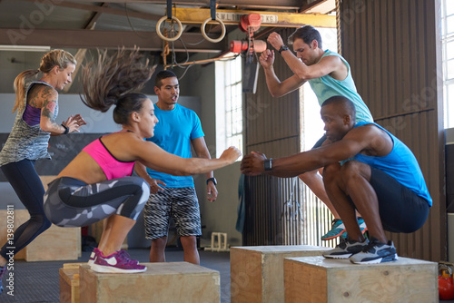 Trainer motivating class doing box jumps fitness boot camp training 