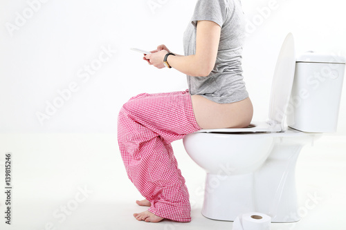 Kobieta na biały tle z telefonem siedzi na sedesie