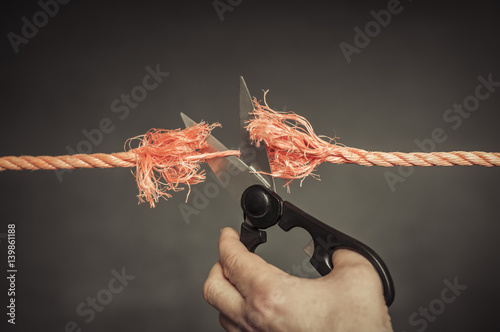 Rotes Seil wird zerschnitten / Rotes Seil wird mit einer Schere zerschnitten.