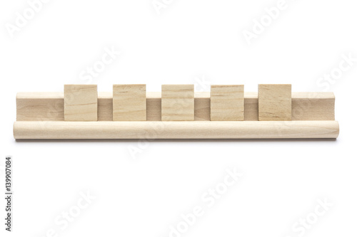 Five blank scrabble tiles on a wooden rack, on white background