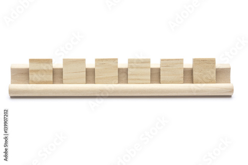 Six blank scrabble tiles on a wooden rack, on white background