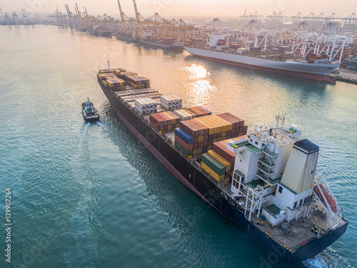 commercial vessel container ship in proceeding arrival to the port channel due, assist by the tugs boat for safety entrance gateway of the port