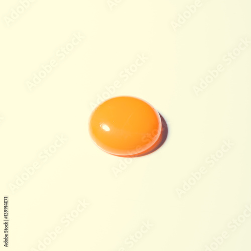 Egg yolk on bright background. Minimal Easter concept.