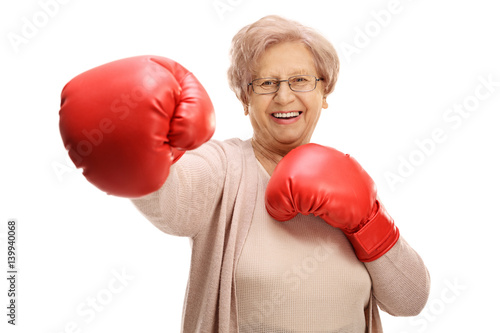 Joyful elderly woman with boxing gloves throwing a punch