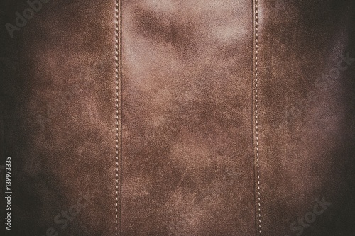 Brown leather texture background surface with seam. Macro shot.