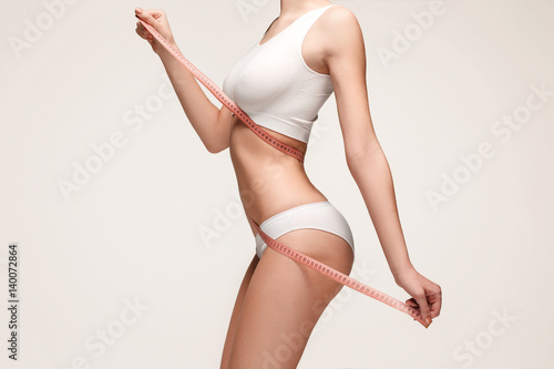 The girl taking measurements of her body, white background.