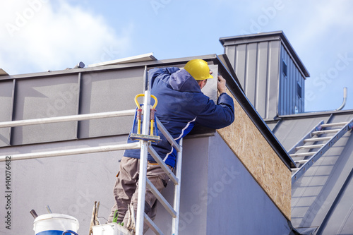 Roofer assembles sheet metal on the roof. Roofers on the roof.