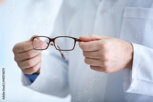 Doctor hands holding glasses on blurred background