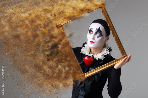 Woman in disguise harlequin in the picture frame. Photo manipulation