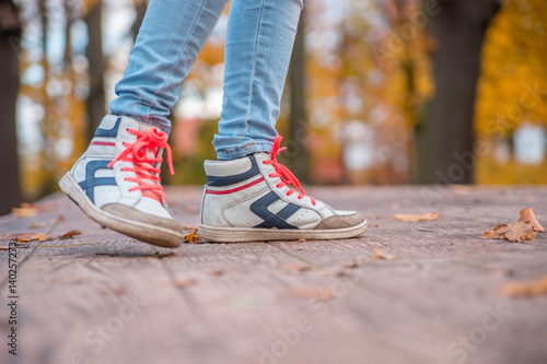 Feet teen in shoes with orange laces, a walk in the autumn Park.