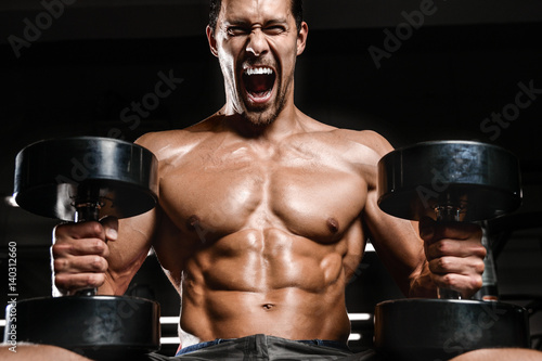 Caucasian sexy fitness male model execute exercise with dumbbells