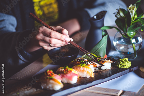 Man eating sushi set with chopsticks on restaurant