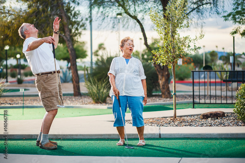 retired couple having fun playing mini golf