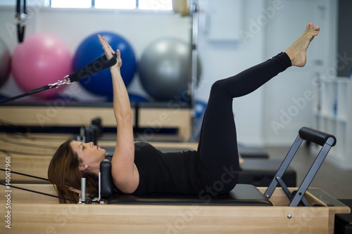 Woman practicing stretching exercise on reformer