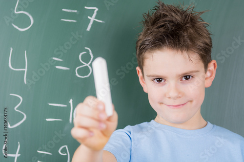 schüler steht an der tafel und löst aufgaben