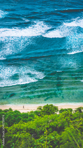 Man walking along of Nunggalan Beach. Big waves rolling on. Uluwatu, Bali, Indonesia