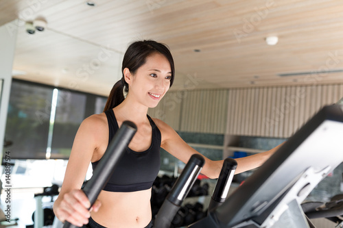Sport Woman training on Elliptical machine in gym