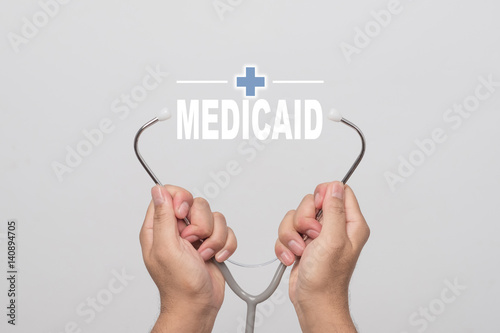 Hands holding a stethoscope and word "MEDICAID" medical concept.