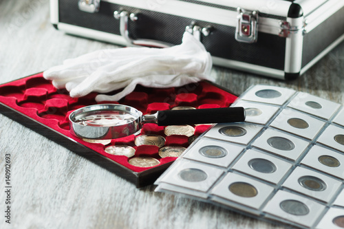 Different collector's coins in the box for coins and a magnifying glass