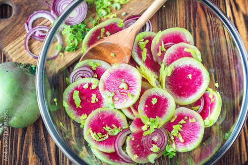 Slices pink fresh watermelon radish onion and celery homemade carpaccio salad for delicious breakfast on wooden table selective focus Healthy eating dieting concept love vegetables Studio photography 