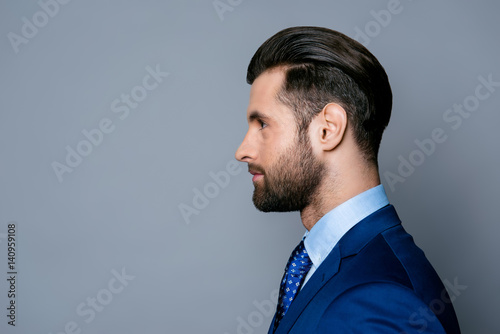 Side view portrait of serious fashionable handsome man in blue suit and tie