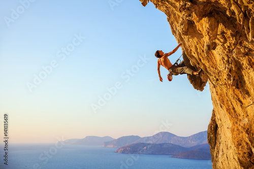 Rock climber on cliff at sunset