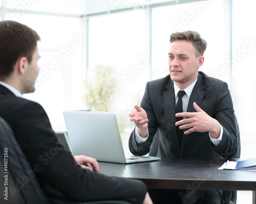Bank employee sitting behind a Desk and talks to the client