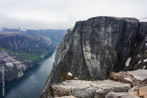 panoramic view of huge Norwegian mountain in front of fjord in cloudy day