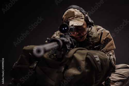 military contracto with his sniper rifle at night. war, army, weapon, technology and people concept