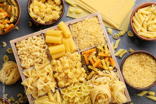 Different kinds of pasta on grey wooden table