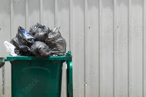 Green garbage bin with black garbage bags.