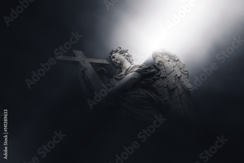 Angel With Cross illuminated by a beam of light